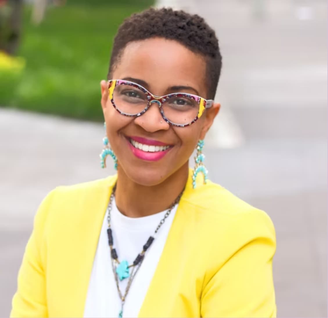 Cyrkle B. Brent, smiling, wearing glasses and a yellow blazer