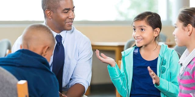 An educator talking with a group of children in a classroom discussion